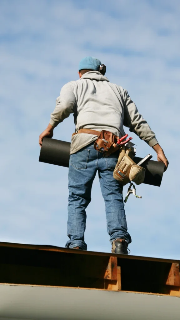 man-on-a-roof-carrying-materials-and-tools-576x1024-1